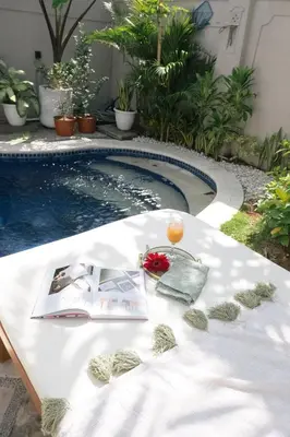 a table with a drink and a book next to a pool at DORALICE by a Paddy Field in Kerobokan