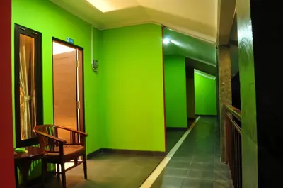 a hallway with green walls and a wooden chair at Amerta Home Stay Bali in Denpasar