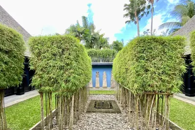 a garden with tall trees in front of a building at Villa Samuan in Seminyak