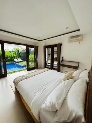 a large white bed in a room with a pool at De'Huta Villa in Canggu