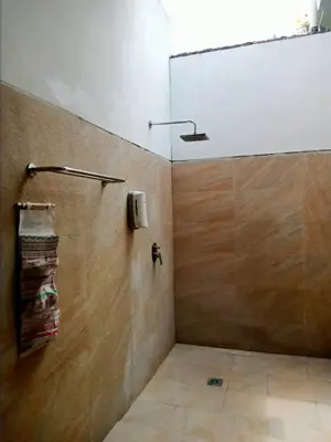 a bathroom with a shower with a wooden wall at De'Huta Villa in Canggu
