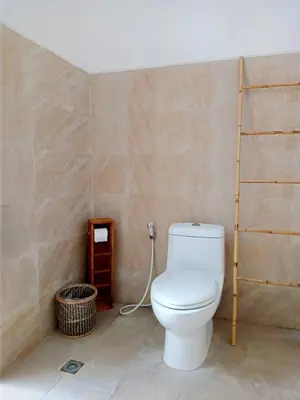 a bathroom with a white toilet in a room at De'Huta Villa in Canggu