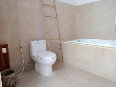 a bathroom with a white toilet and a bath tub at De'Huta Villa in Canggu