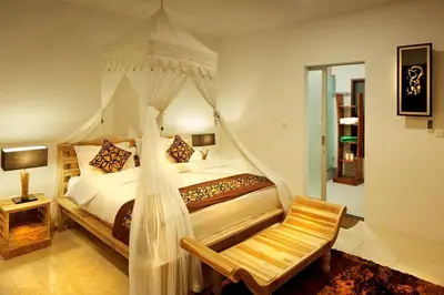 a bedroom with a canopy bed with a chair at Yoga Villa in Seminyak