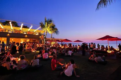 a crowd of people sitting on the beach at night at Yoga Villa in Seminyak