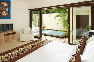 a bedroom with a bed and a tv and a patio at Yoga Villa in Seminyak