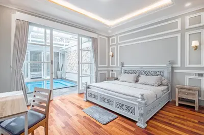 a white bedroom with a bed and a chair at Desa Residence Kerobokan in Kerobokan