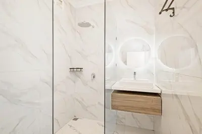 a white bathroom with a sink and a shower at Desa Residence Kerobokan in Kerobokan