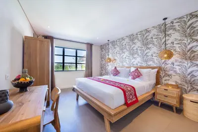 a bedroom with a bed and a desk and a window at Villa ElyOs Canggu by Nagisa Bali in Canggu