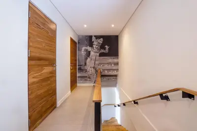a staircase with a wooden door in a house at Villa ElyOs Canggu by Nagisa Bali in Canggu