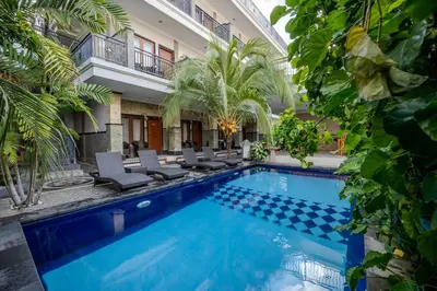 a swimming pool with chairs and a building at Wana Kubu Homestay in Kuta