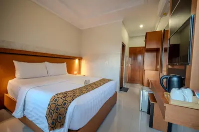 a hotel room with a bed and a television at Wana Kubu Homestay in Kuta