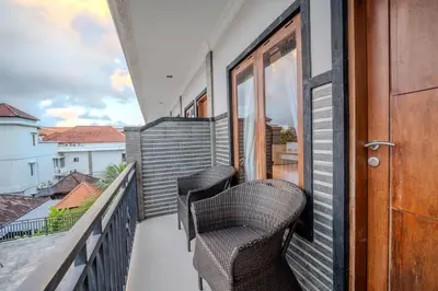 a balcony with two chairs and a door at Wana Kubu Homestay in Kuta