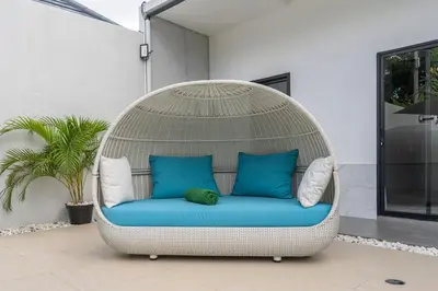 a wicker chair with blue cushions and pillows on a patio at LOTUS - Bali Invest Club in Kerobokan
