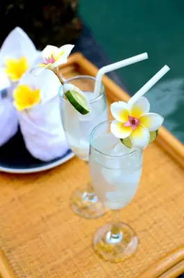 two glasses of water with flowers in them on a tray at Room & Vespa 1 - Stay Central Seminyak Near Beach in Seminyak