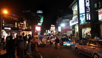 a busy city street at night with cars and people at Graha Wedha Suite Kuta by kamara in Kuta