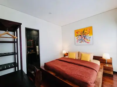 a bedroom with a bed with a red blanket and yellow pillows at Bali 3BR Family Nicho House in Seminyak
