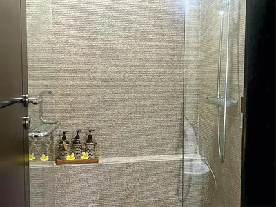 a shower with a glass door with bottles on a shelf at Casa de Prospera - 3BR Villa with Private Pool in Nusa Dua