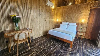 a bedroom with a bed and a desk and a table with a chair at Bamboo Estate Legian in Legian