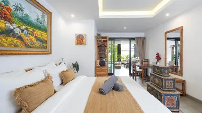 a bedroom with a large white bed and a table at Villa Ambalika by Villa Finder in Seminyak