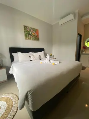 a white bed with white sheets and stuffed animals on it at Queens Villa in Seminyak