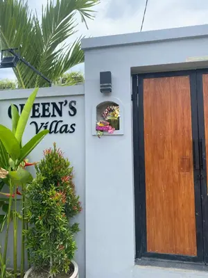 a white house with a wooden door and plants at Queens Villa in Seminyak