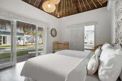 a white bedroom with a bed and a window at Villa Surga Julie by Alfred in Bali in Seminyak