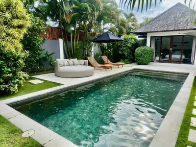 a swimming pool in a backyard with a couch and an umbrella at Villa Iris in Dalung