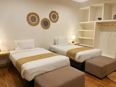 two beds in a room with two ottomans at Maribel Villa Bali in Seminyak