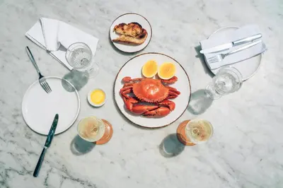 a table with a plate of lobster and glasses of wine at Morabito Art Villa in Canggu