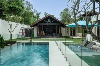 a house with a swimming pool in front of a house at Villa Batu Sari in Canggu