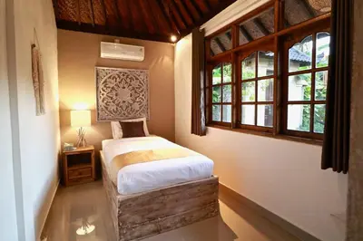 a bedroom with a bed in a room with windows at Villa Santai, huge garden Seminyak square in Seminyak