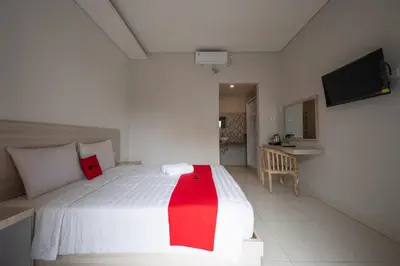 a bedroom with a white bed with a red blanket at RedDoorz Plus at Yasa's Living Denpasar in Sanur