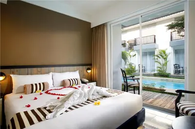 a bedroom with a bed and a balcony with a pool at 7 Bidadari Hotel Seminyak in Seminyak