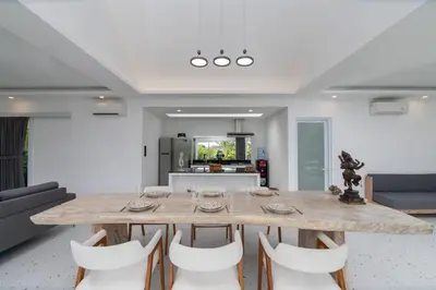 a dining room with a wooden table and white chairs at Villa Vulla in Seminyak