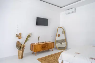 a white bedroom with a wooden dresser and a mirror at New Modern Villa in Bali in Legian