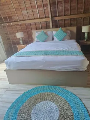 a bed with blue pillows and a rug in a bedroom at Villa Lumbung Krobokan in Seminyak