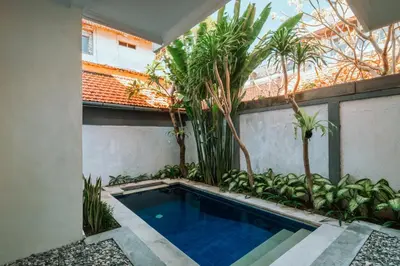 a swimming pool in the middle of a courtyard with trees at Umah Kita Villa in Seminyak