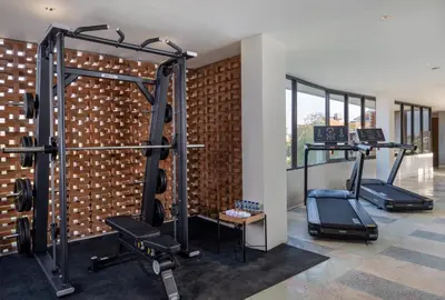 a gym with two tread machines next to a brick wall at Mokko Suites Batubelig in Canggu
