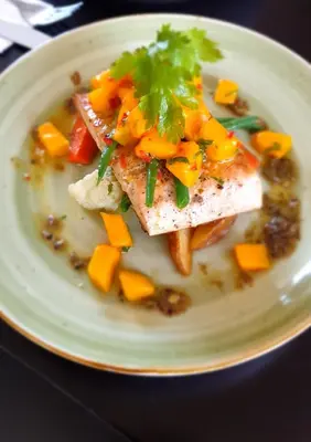 a plate of food with fish and vegetables on it at Mokko Suites Batubelig in Canggu
