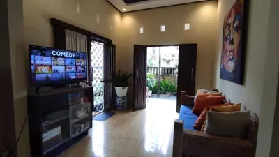 a living room with a television and a couch at Moara Guest House in Kerobokan