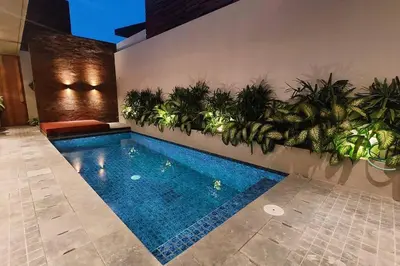 a swimming pool with plants on a wall at Villa Akhila 2 - 2 BR modern tropical villa at the heart of Seminyak in Seminyak
