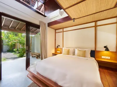 a bedroom with a large bed and a large window at Bumbak Park Villas By Nakula in Canggu