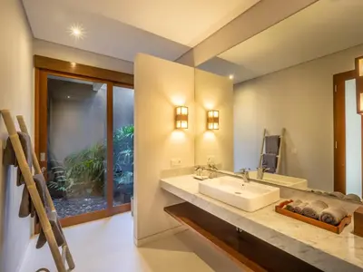 a bathroom with a sink and a large mirror at Bumbak Park Villas By Nakula in Canggu