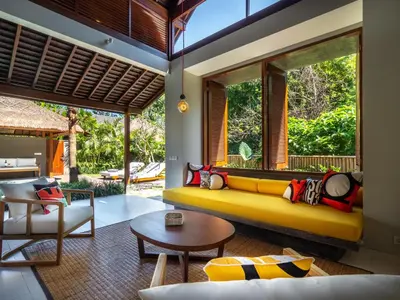 a living room with a yellow couch and a table at Bumbak Park Villas By Nakula in Canggu