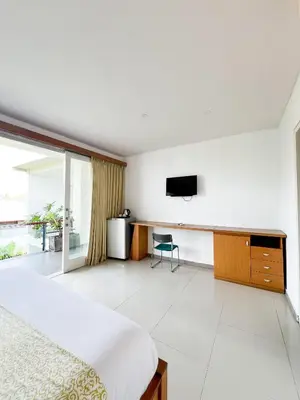 a bedroom with a bed and a tv on a wall at Apple Suite in Kerobokan