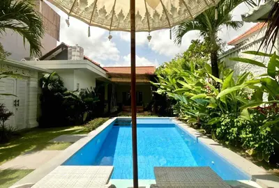 a swimming pool with an umbrella in front of a house at Incredible villa near Atlas beach club Berawa in Canggu