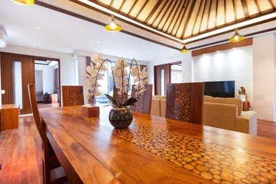 a dining room with a wooden table with a vase on it at Bali - Jimbaran Beach Villa Private Pool in Jimbaran
