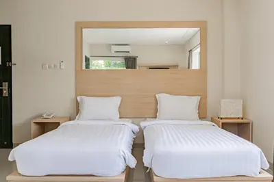 two beds in a room with a mirror at Collection O Kuta Near Airport Ngurah Rai in Kuta