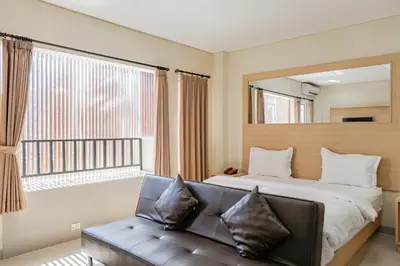 a bedroom with a bed and a couch and a window at Collection O Kuta Near Airport Ngurah Rai in Kuta